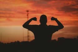 A silhouette of a strong man under a cloudy sky during the golden sunset