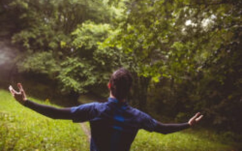 Excited athlete with his arms outstretched in forest