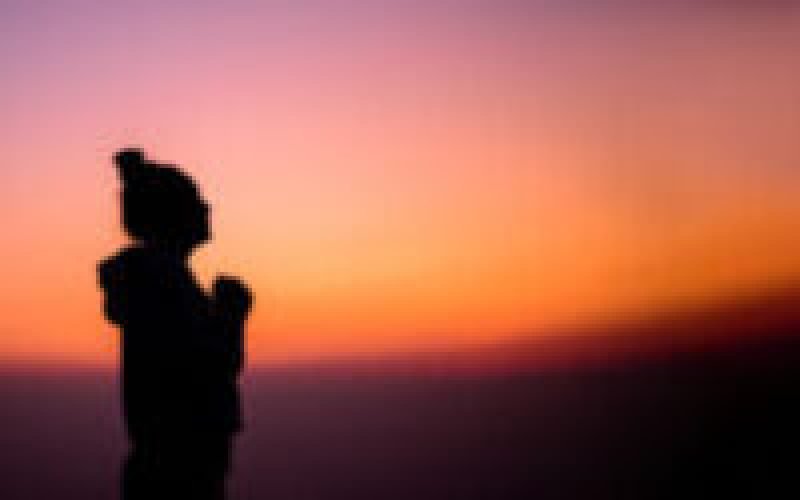 Silhouette of Side view portrait of a woman praying and looking above at sunset with copy space. Travel Lifestyle wanderlust adventure concept summer vacations outdoor.